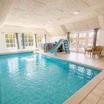 Innenpool mit Rutsche und Whirlpool, große Fenster und Terrasse.