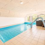 Indoorpool mit Rutsche und Whirlpool. Tageslicht durch Fenster.