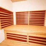 Sauna mit Holzbank und roten Paneelen an den Wänden.
