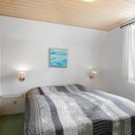 Schlafzimmer mit Bett, Wandbild und Fenster. Holzdecke und grüner Boden.
