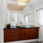 Badezimmer mit Holzschrank, Waschbecken und Spiegel. Fenster mit Vorhang.