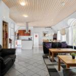 Wohn- und Essbereich mit schwarzen Sofas, Holztischen und hohem Holzdecken