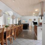 Großer Essbereich mit Holztisch, Stühlen und Deckenleuchten. Küche und Wohnzimmer im Hintergrund.