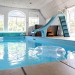 Innenpool mit Rutsche und Schwimmringen. Große Fenster und Dachfenster.