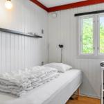 Ein Schlafzimmer mit weißer Wandverkleidung, einem Bett und einem Fenster mit Blick auf Grün.