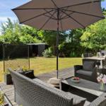 Terrasse mit Sitzgruppe, Sonnenschirm und Grillbereich im Garten.