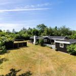 Haus mit Garten und Wald im Hintergrund unter blauem Himmel.