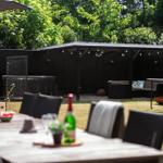 Hinterhof mit Grill, Sitzgelegenheiten und Feuerkorb. Tisch mit Flasche und Obst.