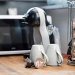 Kaffeemaschine mit Kapseln und Tassen auf Küchenarbeitsfläche