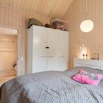Schlafzimmer mit Holzwand, weißem Schrank und Bett mit Kissen.