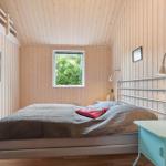Schlafzimmer mit Holzwänden, Bett, Nachttisch und Fenster mit Blick auf Grün.
