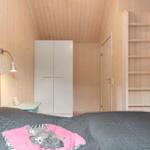Schlafzimmer mit Holzwand, Bett, Kleiderschrank und Leiter.