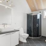 Badezimmer mit Dusche, Toilette und Waschbecken unter Spiegel.
