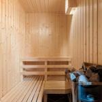 Sauna mit Holzwandverkleidung, Sitzbänken und Steinbehälter.