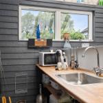 Küche mit Holzplatte, Spüle und Fenster mit Blick auf Grün.