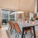 Essbereich mit Holzdecke und Küchenzeile. Tisch mit braunen Stühlen und Glas.