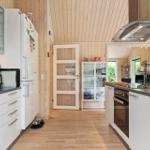 Moderne Küche mit weißen Schränken, Holzboden und Holzwandverkleidung.