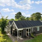 Ein modernes Haus mit Terrasse und Garten unter blauem Himmel.