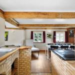 Küche mit Steinwand, Essbereich und Holzbalken an der Decke.
