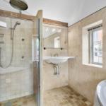 Badezimmer mit Dusche, Waschbecken und Badewanne. Fliesenwand und Fenster.