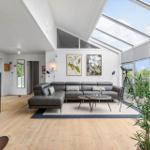 Wohnzimmer mit grauem Sofa, Holzboden und großem Dachfenster.