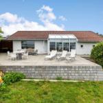 Haus mit Terrasse, Sonnenliegen und Grillplatz. Grünanlagen umgeben die Außenbereiche.