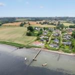 Haus am Wasser mit Bootssteg und umliegenden Feldern.