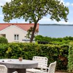 Haus mit Blick auf See, Gartenbereich mit Tisch und Stühlen.