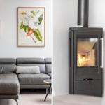 Graue Ledercouch mit Kissen unter einem Blumenbild. Holzofen mit brennendem Feuer.