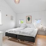 Schlafzimmer mit Bett, Fenstern und Wandbildern. Holzboden und weiße Wände.