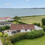 Wohnhaus mit Terrasse, umgeben von Grünflächen und einem See.