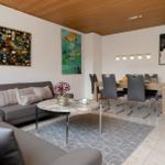 Wohn- und Essbereich mit Sofa, Tisch und Stühlen sowie Wandbildern.