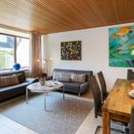 Wohn- und Essbereich mit Sofa, Esstisch und Wandbildern.