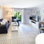 Living room with sofa, TV, and fireplace. Doorway to terrace with garden view.