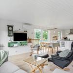 Wohnzimmer mit Kamin, TV und Essbereich. Holzboden und weiße Wände.