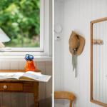 Schreibtisch mit Lampe und Buch neben Fenster. Spiegel und Hut an Wand.