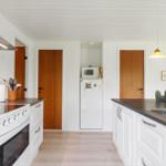 Küche mit weißen Schränken, dunklem Arbeitsplatz und integriertem Kühlschrank.