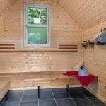 Sauna mit Holzwand, Fenster, Bänken und Saunahut