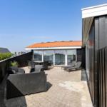 Terrasse mit Sitzgruppe, Liegen und Blick auf Poolbereich.