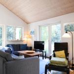 Wohnzimmer mit Sofa, Sessel, Fernseher und Holzdecke.