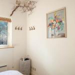 Ein Raum mit Fenster, Wandbild und Haken. Ein gestreifter Korb steht im Ecke.