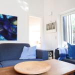 Ein Wohnzimmer mit blauem Sofa, Holztisch und Wandbildern.