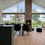 Moderne Küche mit Essbereich, Kamin und großem Fensterblick auf Grünland.