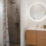 Dusche mit floraler Gardine und Waschbecken mit runden Spiegel.