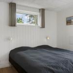 Schlafzimmer mit Bett, Fenster und weißen Wänden.