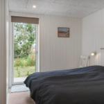 Schlafzimmer mit Bett, Fenster und Wandbild.
