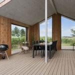 Terrasse mit Esstisch, Grill und großzügigen Fenstern zur Landschaft.