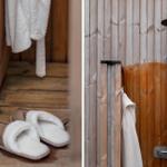 Holzverkleidete Dusche mit Duschbrause und Handtuch. Weiße Frottierbademantel und Hausschuhe auf Holzboden.