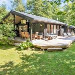 Haus mit Holzterrasse, Garten und Sitzgelegenheiten im Grünen.