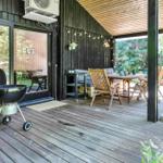 Terrasse mit Grill, Tisch und Stühlen. Holzdecke und Pflanzen im Hintergrund.